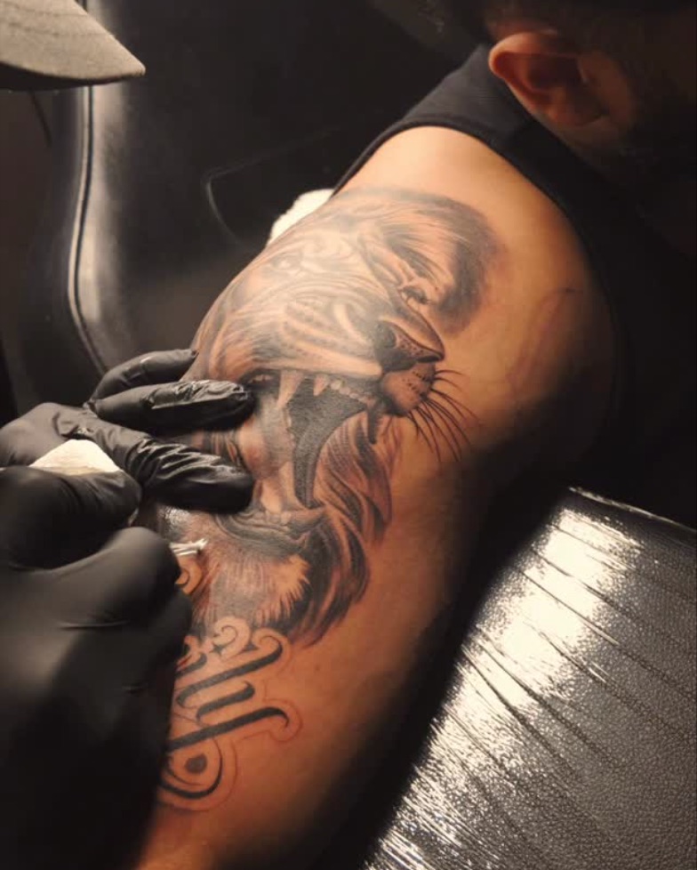 Vik tattooing a lion on a client's arm
